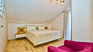 Een slaapkamer met een bed, een nachtkastje, een stoel en een raam met gordijnen.