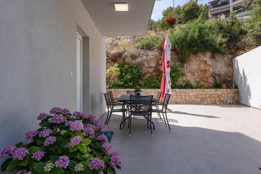 Une terrasse extérieure avec une table et des chaises, un pot de fleurs et un drapeau.