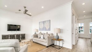 A modern living room with a sofa, a coffee table, a TV, and artwork on the wall. - Beachfront Bliss Beach House (Orange Beach)