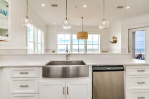 A modern kitchen with a stainless steel sink, white cabinets, and pendant lights. - Beachfront Bliss Beach House (Orange Beach)