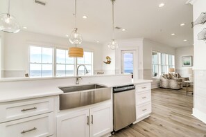 A modern kitchen with a large island, stainless steel appliances, and pendant lighting. - Beachfront Bliss Beach House (Orange Beach)