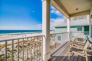 A beach view from a covered porch with a railing, overlooking the ocean and beach. - Beachfront Bliss Beach House (Orange Beach)