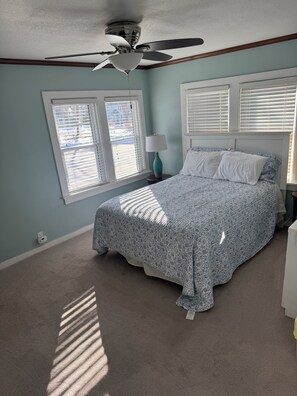 A bedroom with a bed, a ceiling fan, and a window with blinds.