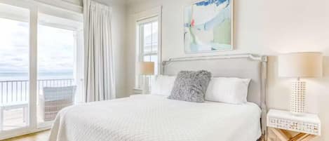 A hotel room with a large bed, a view of the sea, and a painting on the wall.