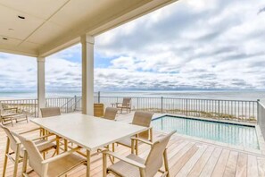 A covered outdoor area with a pool, a table, and chairs. - Beach Vista One Beach House (Orange Beach)