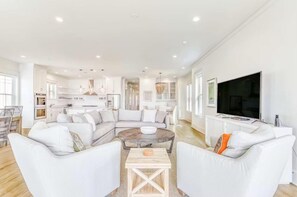 A spacious living area with a large sectional sofa, a coffee table, and a television. - Beach Vista One Beach House (Orange Beach)