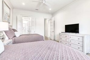 A bedroom with two beds, a television, a dresser, and a ceiling fan. - Beach Vista One Beach House (Orange Beach)