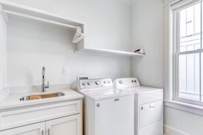 A laundry room with a sink, two washing machines, and a window. - Beach Vista One Beach House (Orange Beach)