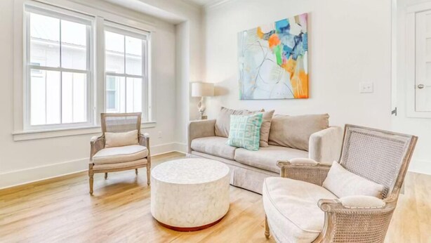 A spacious living room with a large window, a round coffee table, and a sofa with cushions. - Beach Vista One Beach House (Orange Beach)