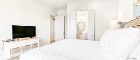 A bedroom with a large bed, a television, a dresser, and a wardrobe.