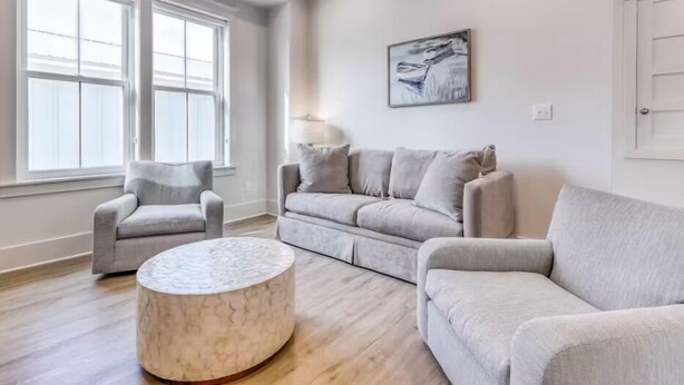 A living room with a grey sofa, a grey armchair, and a marble coffee table. - Beach Vista Two Beach House (Orange Beach)