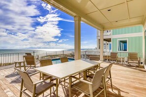 A covered outdoor area with a pool table, chairs, and a view of the ocean. - Beach Vista Two Beach House (Orange Beach)