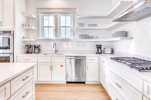 A modern kitchen with white cabinetry, a stainless steel dishwasher, and a gas stove. - Beach Vista Two Beach House (Orange Beach)