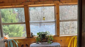 A room with a table and two chairs, a window with a view of trees, and a patterned rug.
