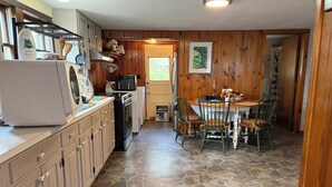 A kitchen with a stone floor, wooden cabinets, and a dining area with chairs and a table.
