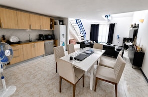A modern kitchen with wooden cabinets, a white refrigerator, and a dining area with a white table and chairs.