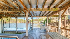 A covered deck with a pool, wooden benches, and a view of a lake. - Spacious Waterfront Home on Smith Mountain Lake (Moneta)