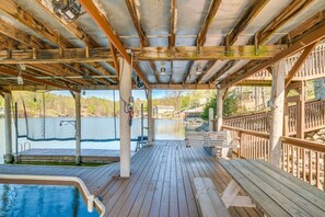 A covered deck with a pool, wooden benches, and a view of a lake. - Spacious Waterfront Home on Smith Mountain Lake (Moneta)