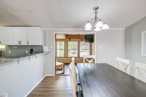 A kitchen with white cabinets, a wooden dining table, and a bench. - Spacious Waterfront Home on Smith Mountain Lake (Moneta)