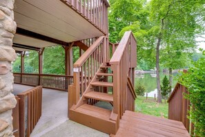 A wooden staircase leading to a covered deck with a view of a lake and trees. - Spacious Waterfront Home on Smith Mountain Lake (Moneta)
