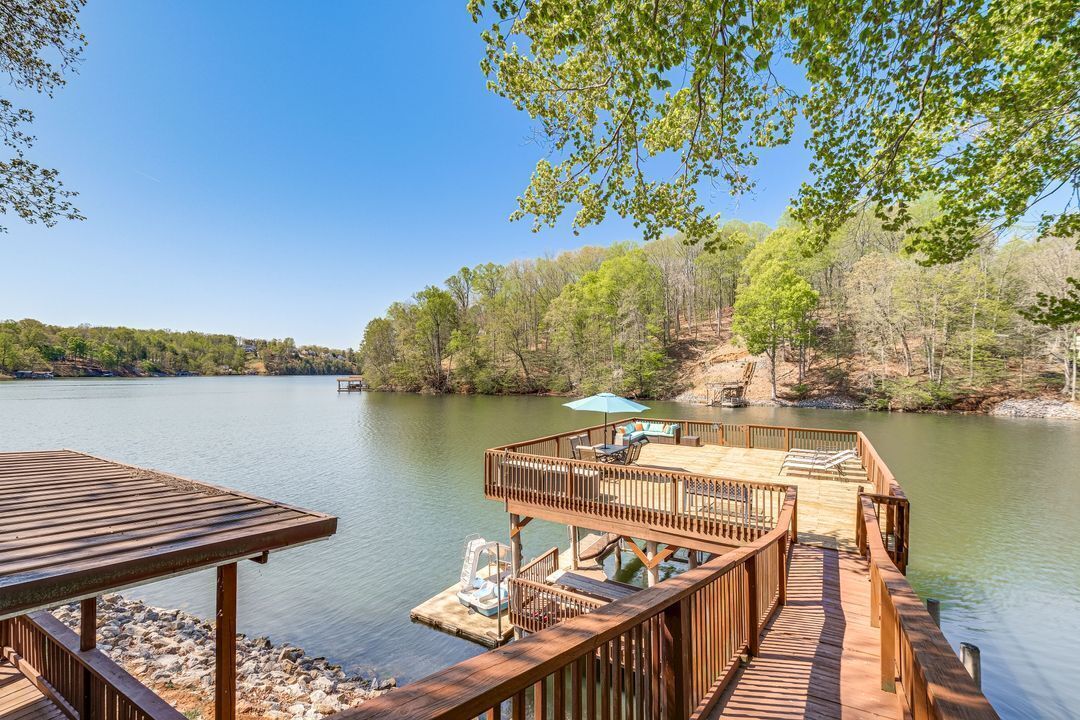 Une terrasse en bois offrant une vue sur un lac paisible et des collines boisées.