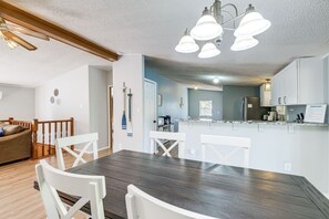 A dining area with a wooden table and white chairs, a kitchen in the background, and a ceiling fan. - Spacious Waterfront Home on Smith Mountain Lake (Moneta)