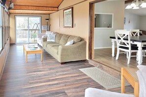 A living room with a sofa, coffee table, and a dining area with chairs and a table. - Spacious Waterfront Home on Smith Mountain Lake (Moneta)