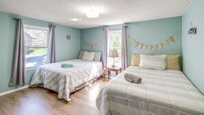 A room with two beds, a window with curtains, a small table with a lamp, and a wall decoration. - Spacious Waterfront Home on Smith Mountain Lake (Moneta)