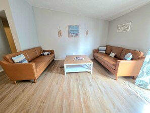 A living room with two brown sofas, a wooden coffee table, and a painting on the wall.