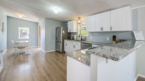 A modern kitchen with white cabinets, a granite countertop, and a built-in refrigerator. - Spacious Waterfront Home on Smith Mountain Lake (Moneta)
