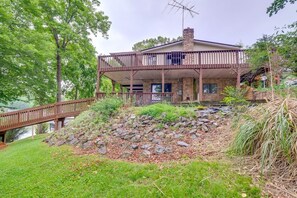 A two-story house with a balcony, a stone chimney, and a wooden deck. - Spacious Waterfront Home on Smith Mountain Lake (Moneta)
