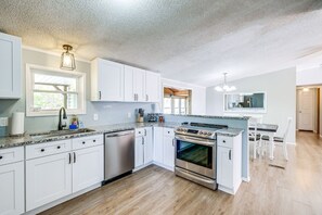 A modern kitchen with white cabinets, stainless steel appliances, and a granite countertop.