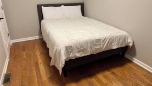 A single bed with a dark headboard in a room with wooden flooring and light-colored walls. - 4BR Downtown Retreat | Free Street Parking (Chicago)