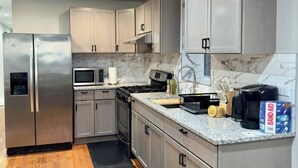 A modern kitchen with stainless steel appliances, marble backsplash, and wooden flooring. - 4BR Downtown Retreat | Free Street Parking (Chicago)