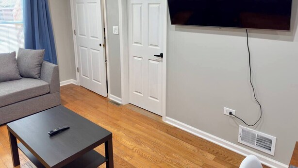 A living room with a sofa, a coffee table, and a flat-screen TV mounted on the wall. - 4BR Downtown Retreat | Free Street Parking (Chicago)