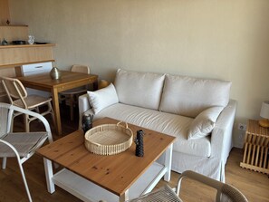 Een gezellige zithoek met een bank, een houten tafel en rieten stoelen.
