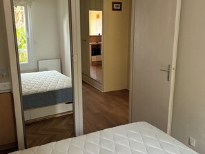 Een slaapkamer met een bed, een garderobe en een spiegel.