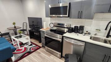 Una cocina compacta con electrodomésticos modernos, un comedor con un sofá azul y una pequeña mesa.