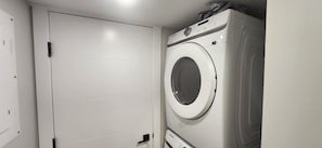 Ein Waschraum mit einer weißen Tür und einer Samsung Waschmaschine.