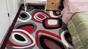 Een slaapkamer met een bed, nachtkastje, lamp en een kamerbreed tapijt.