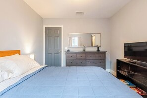 Ein Schlafzimmer mit Bett, Kommode, Spiegel und Fernseher.
