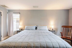A bedroom with a large bed, two bedside tables, a chair, and a window with curtains. - Spacious 3BR · Private Patio · Near Austin (Pflugerville)