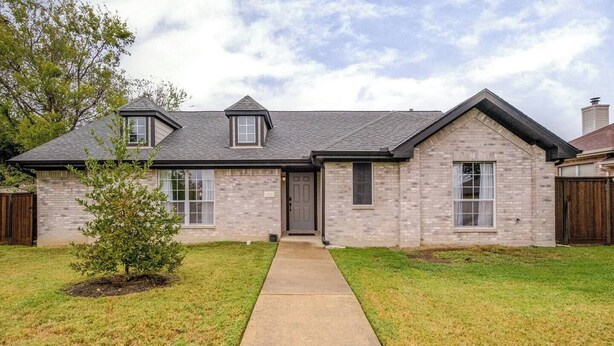 A two-story house with a brick exterior, a front porch, and a small tree in the yard. - Spacious 3BR · Private Patio · Near Austin (Pflugerville)
