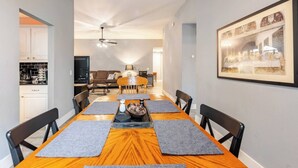 A dining area with a long wooden table, black chairs, and a ceiling fan. - Spacious 3BR · Private Patio · Near Austin (Pflugerville)
