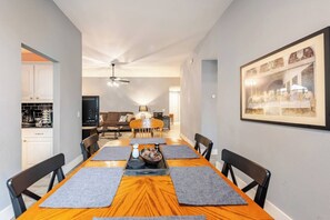 A dining area with a long wooden table, black chairs, and a ceiling fan. - Spacious 3BR · Private Patio · Near Austin (Pflugerville)