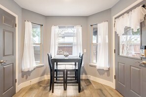 A dining area with a table and chairs, a window with curtains, and a door with a handle. - Spacious 3BR · Private Patio · Near Austin (Pflugerville)