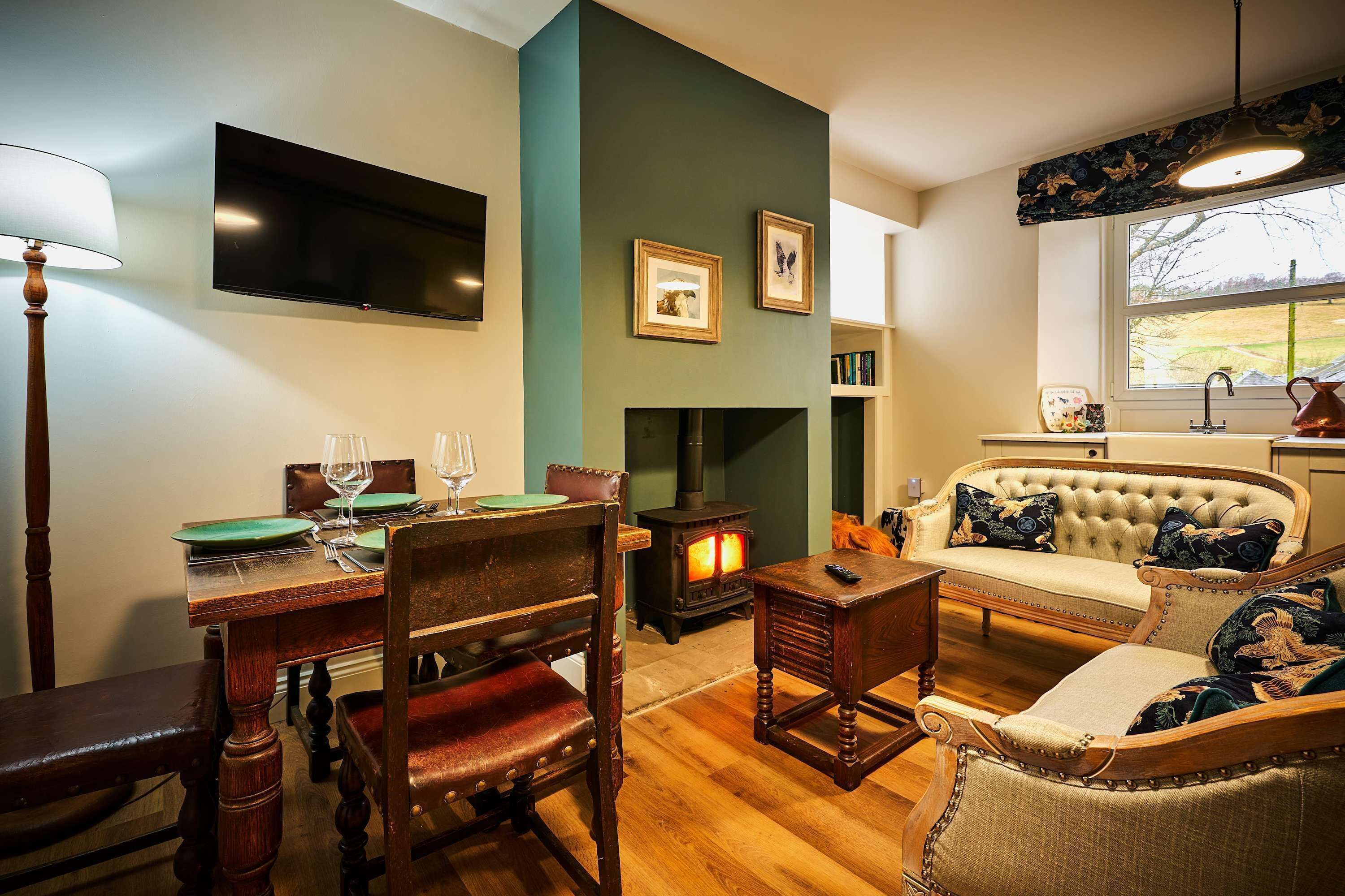 A cozy living room with a fireplace, a dining table set for two, and a comfortable sofa.