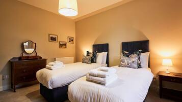 A hotel room with two beds, a dresser, a mirror, and a lamp.