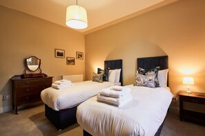 Une chambre d’hôtel avec deux lits, une commode, un miroir et une lampe.