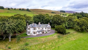 A large, historic house with a driveway leading to a gated entrance, surrounded by lush greenery and rolling hills. - Kinclune House Buildings on Private Angus Estate (Kirriemuir)